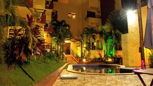 Un patio de hotel con piscina, palmeras y una escalera que lleva al edificio.