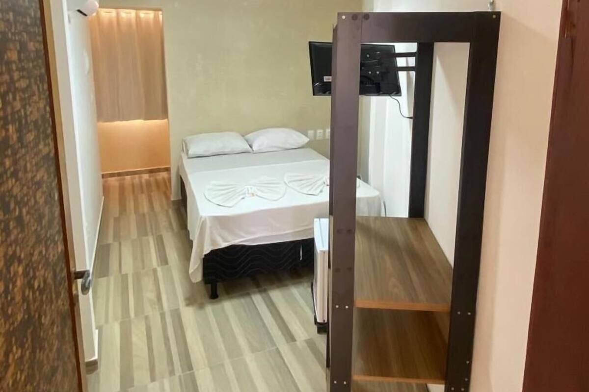Una habitación de hotel con cama, televisor y suelo de madera.