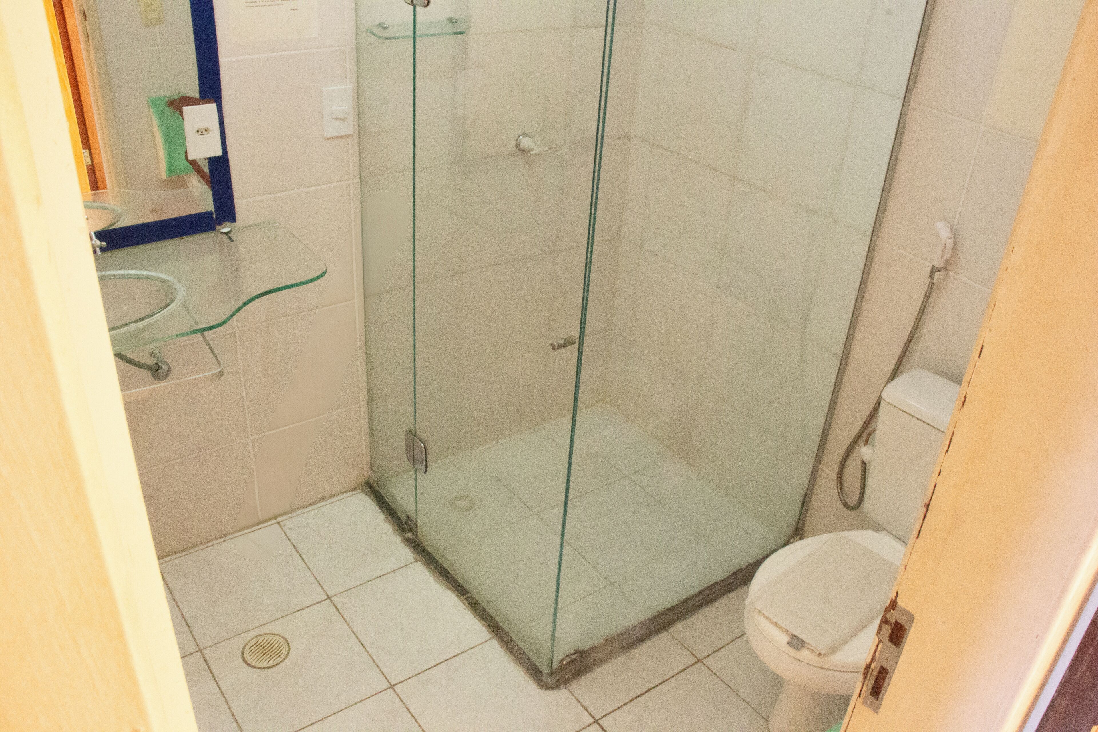 A bathroom with a glass shower enclosure, a toilet, and a sink with a glass countertop.