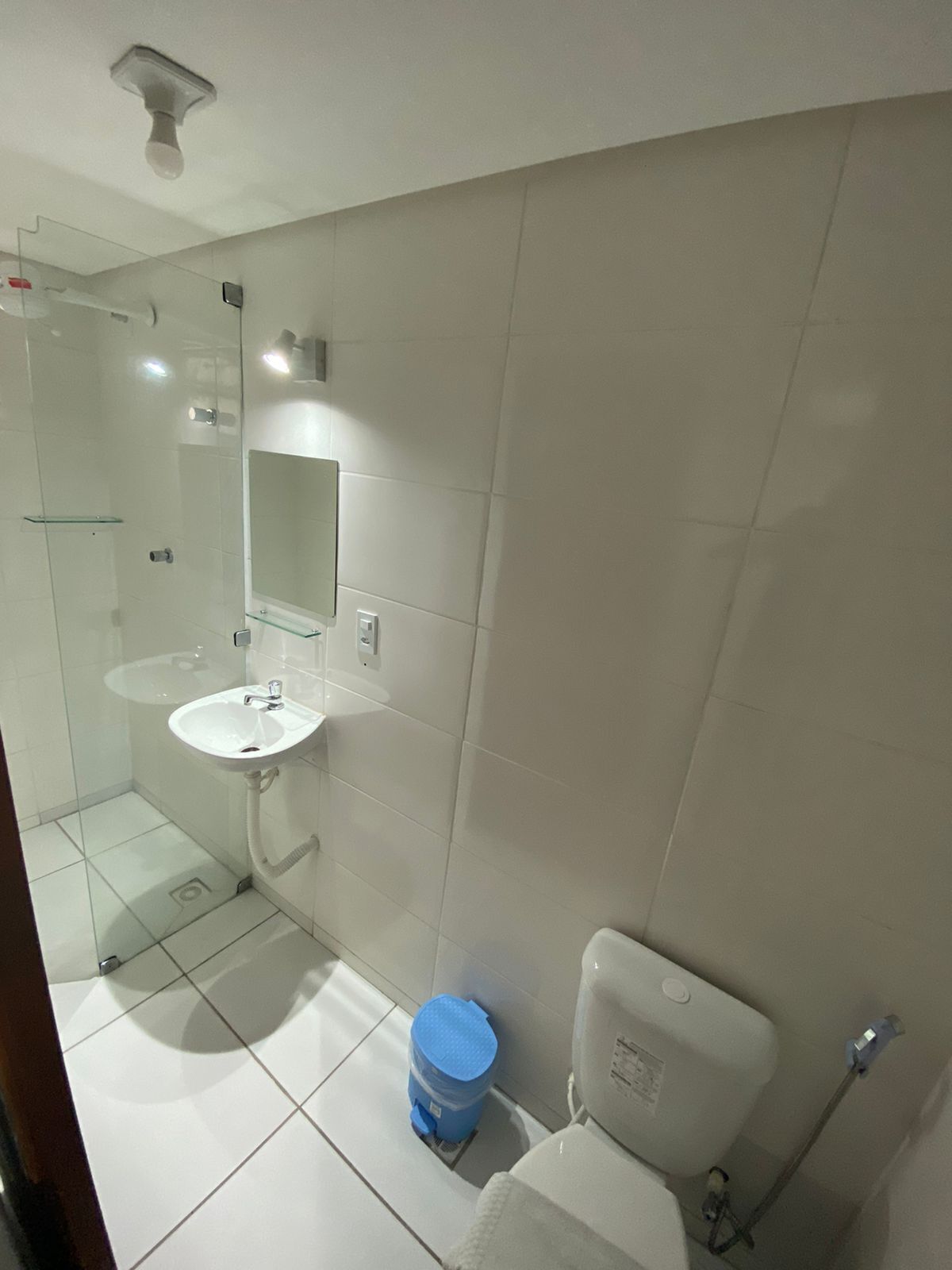 A bathroom with a glass shower enclosure, a white sink, a mirror, and a toilet.