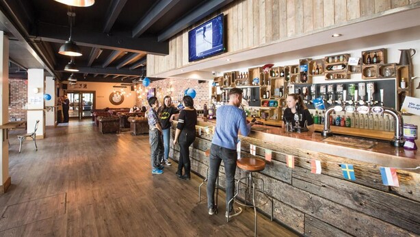 Un espace bar avec un plancher en bois, un comptoir et un téléviseur fixé au mur.