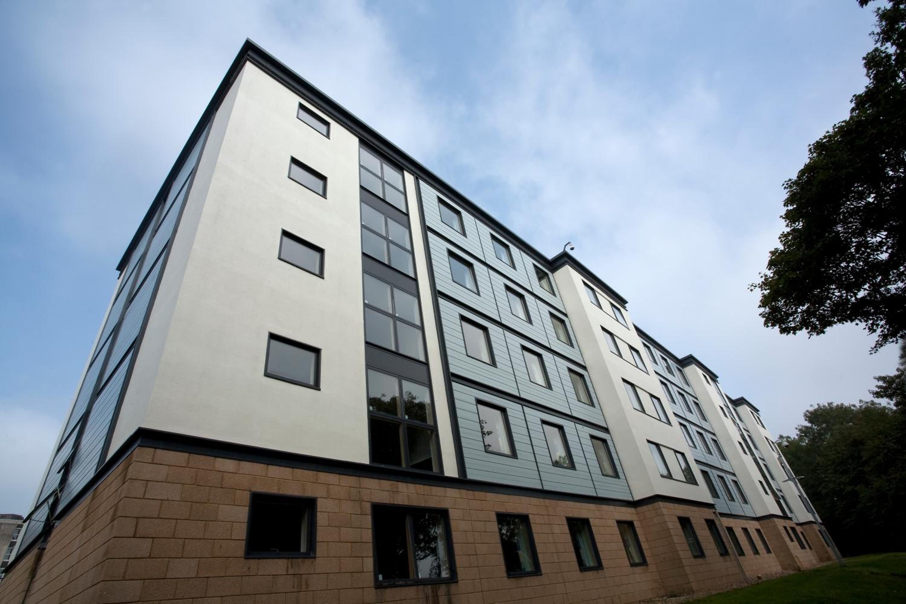 A multi-story building with a modern architectural design, featuring a mix of large windows and a brick base.