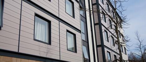A multi-story building with a modern architectural design, featuring a combination of brick and light-colored panels.