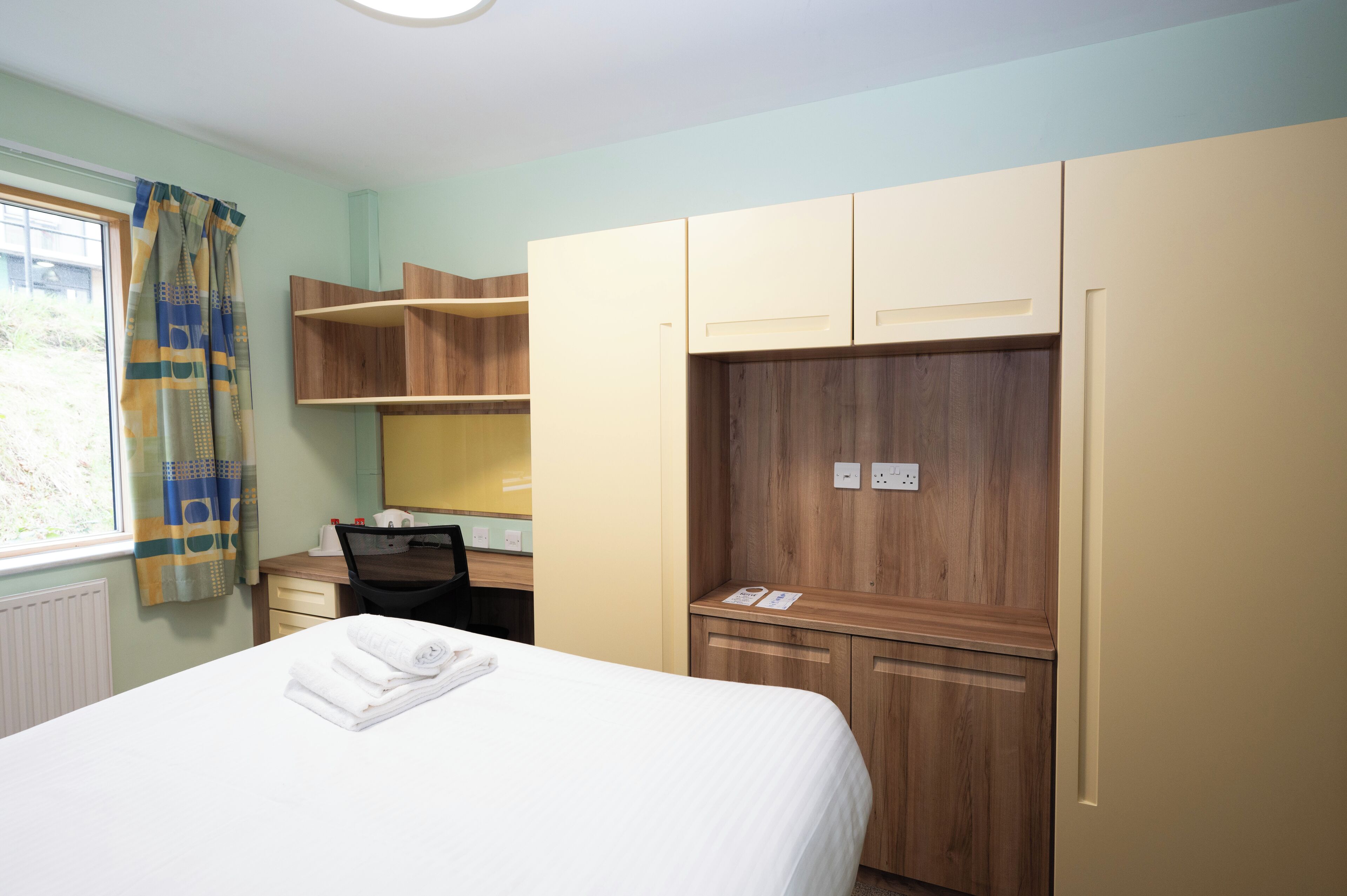 Una habitación de hotel con cama, escritorio y armario.