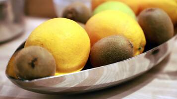 A metal tray with oranges and kiwis on a table.