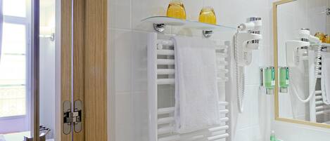 Een moderne badkamer met een glazen plankje met toiletartikelen, een witte handdoekhouder en een grote spiegel.