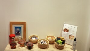 A wooden shelf with jars, baskets, and a bottle, against a wall with a black line design. - Best Western Hotel du Mucem (Marseille)