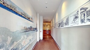 A hallway with a mural on the left and a series of black-and-white drawings on the right. - Best Western Hotel du Mucem (Marseille)
