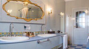 A bathroom with two sinks, a large ornate mirror, a towel rack, and a door with frosted glass panels. - Agrirelais Baglio di Pianetto (Santa Cristina Gela)