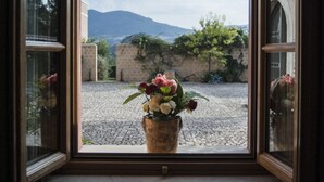 A window with a view of a courtyard, a potted plant, and a clear sky. - Agrirelais Baglio di Pianetto (Santa Cristina Gela)