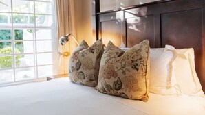 A neatly made bed with floral pillows and a white comforter. - Maison Chablis (Franschhoek)