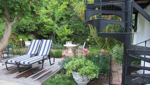 A patio with two striped lounge chairs, a small table, and a potted plant. - Maison Chablis (Franschhoek)