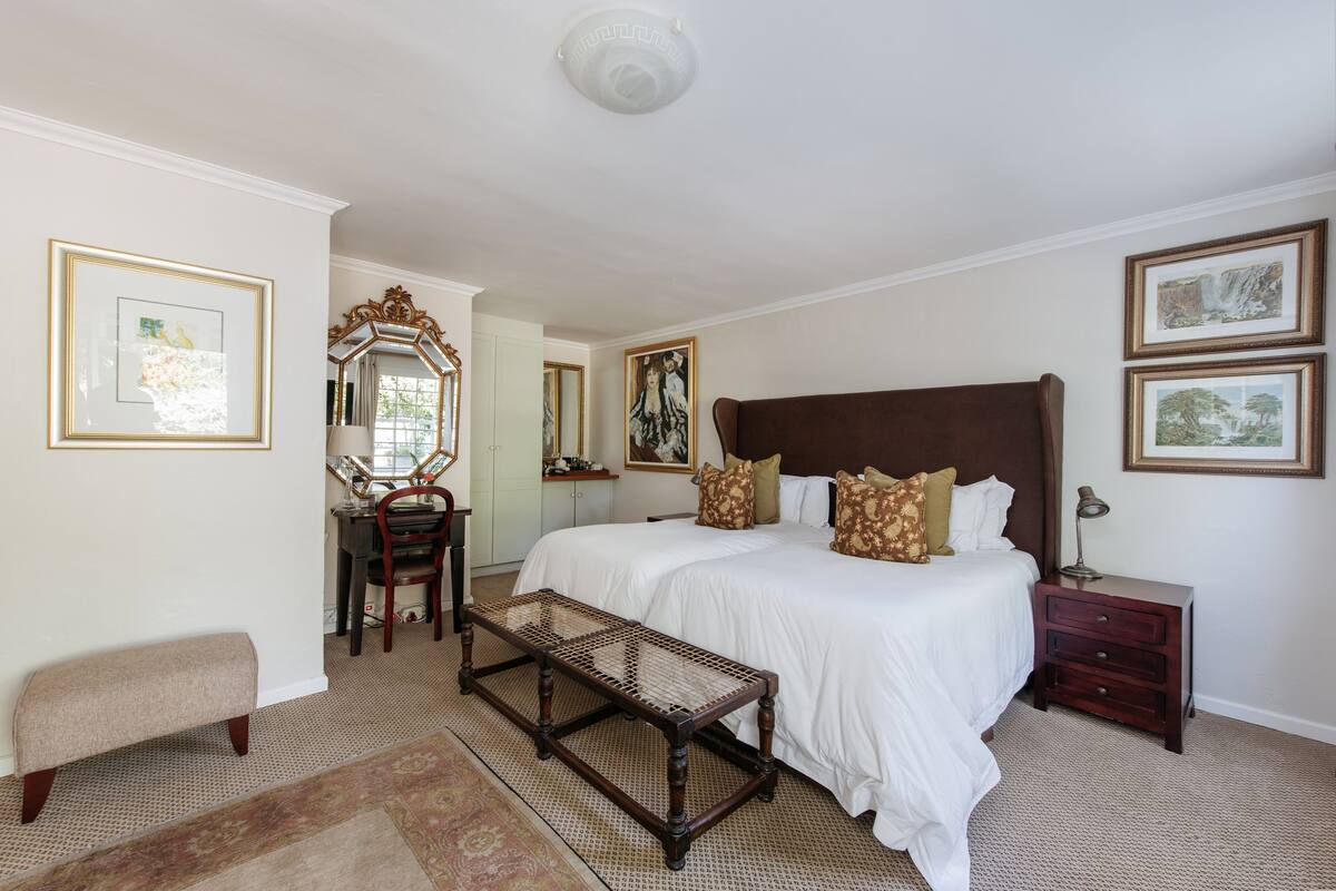 Une chambre à coucher avec un grand lit, un banc en bois, un bureau et une commode.