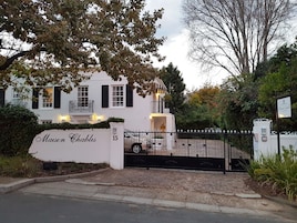 A white building with black shutters, a gated entrance, and a sign reading "Maison Chablis."