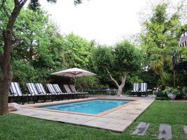 Una piscina al aire libre, sombrillas, sillones reclinables de piscina