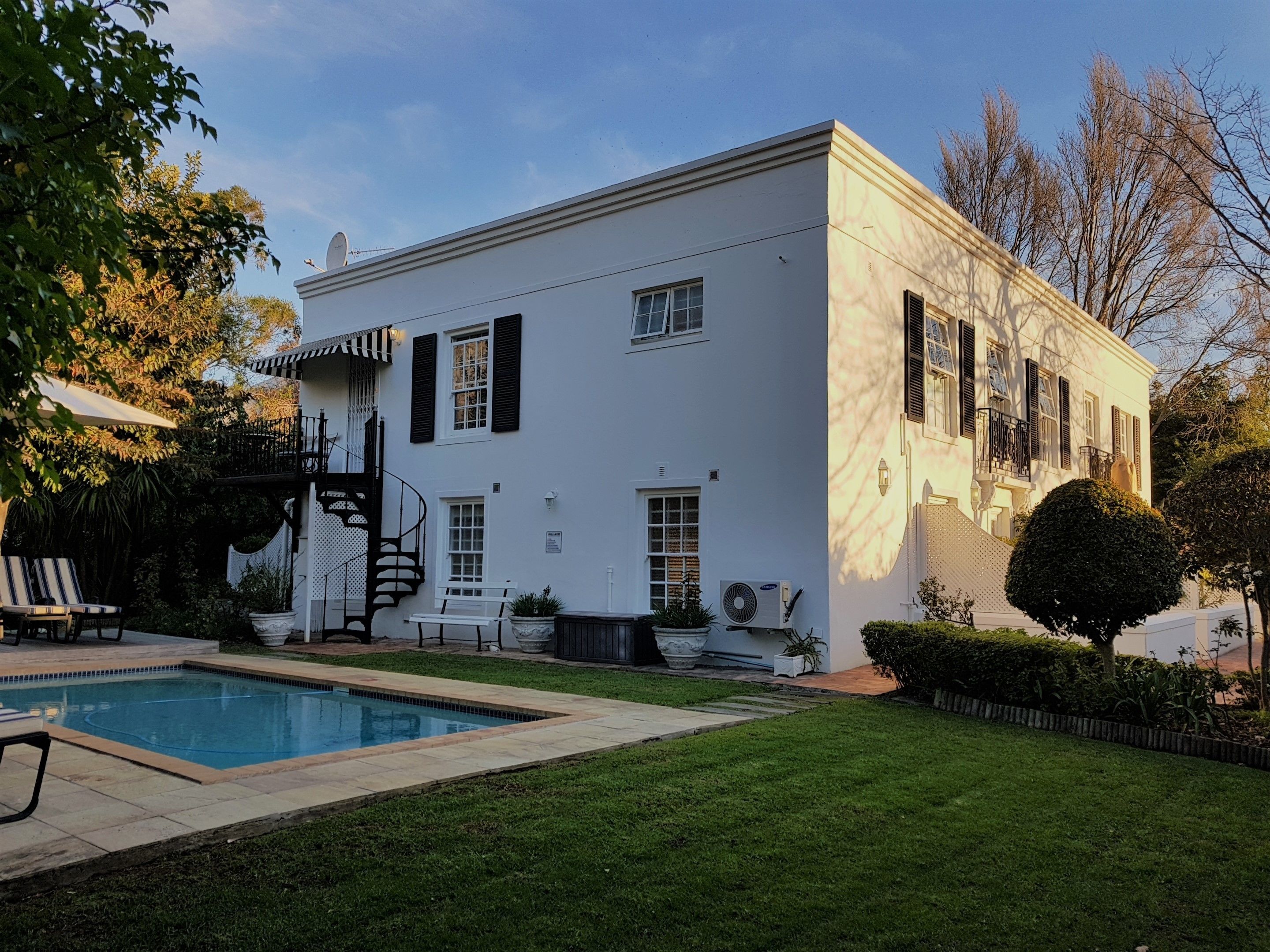 Un edificio blanco con piscina, escaleras y un pequeño jardín.