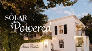A white house with a number 15 sign, solar power text, and a garden. - Maison Chablis (Franschhoek)
