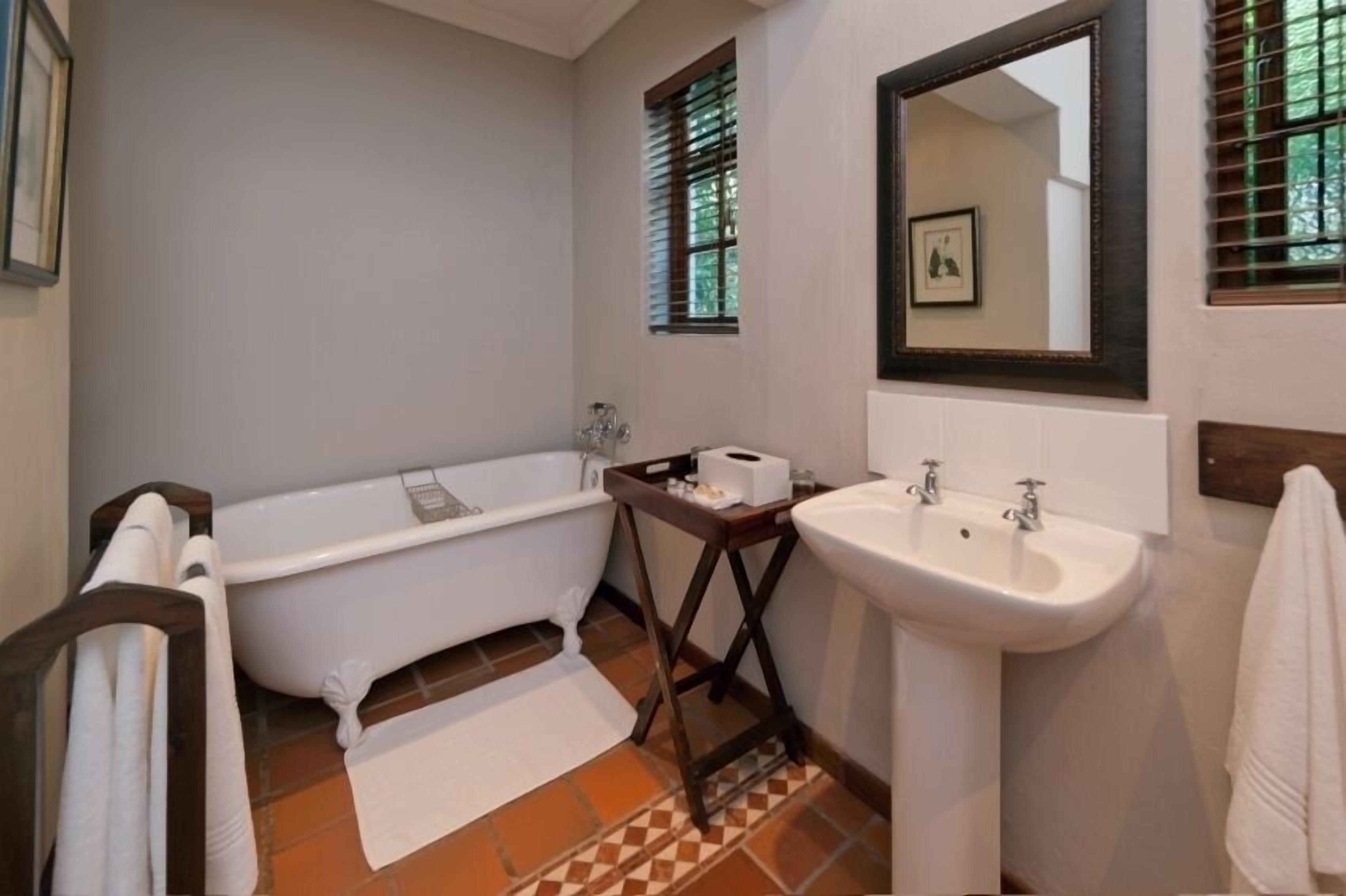 A bathroom with a white bathtub, a sink, and a mirror.