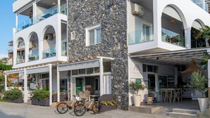 Un hotel moderno con fachada de piedra, varios balcones y zonas de estar al aire libre.