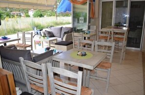 An outdoor patio area with wooden furniture, including tables and chairs, and a sofa.