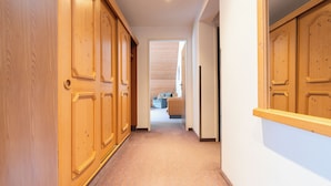 Un pasillo con armarios de madera, suelo alfombrado y vistas a un salón con un sofá y una mesa de centro.