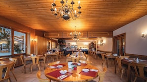 Un comedor amplio con mesas y sillas de madera, candelabros y vistas al exterior.
