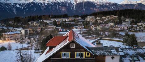 Un edificio de varios pisos con techo rojo, rodeado de montañas nevadas.