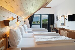 Habitación de hotel con techo de madera, un ventanal con vistas a la montaña, televisor de pantalla plana y escritorio con silla.
