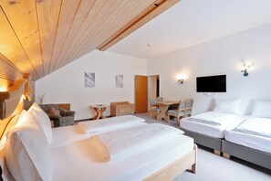 Habitación de hotel con techo de madera, cama, escritorio, silla y televisión.