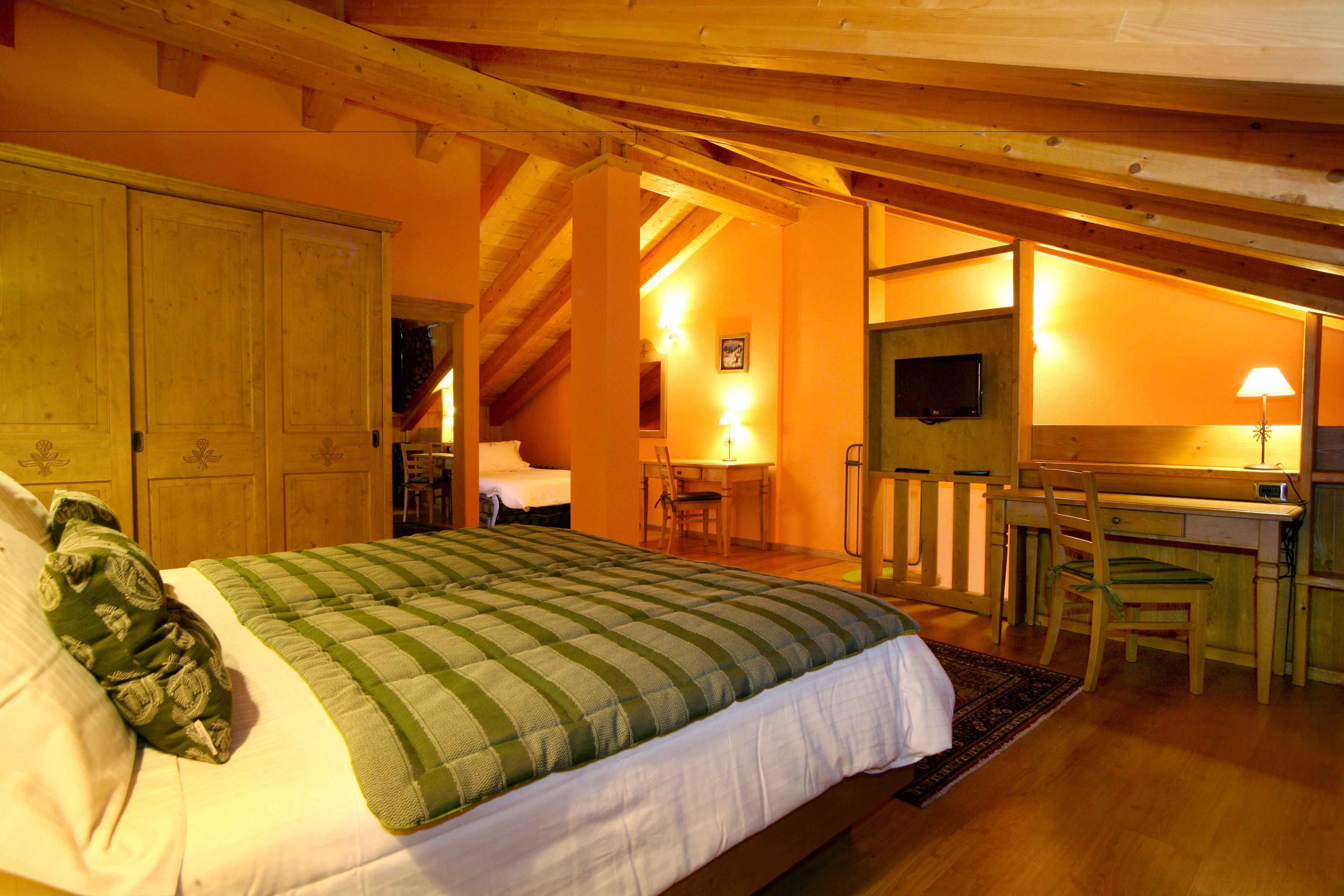 Une chambre à coucher comprenant un lit, une armoire en bois, un bureau, une chaise et un téléviseur.