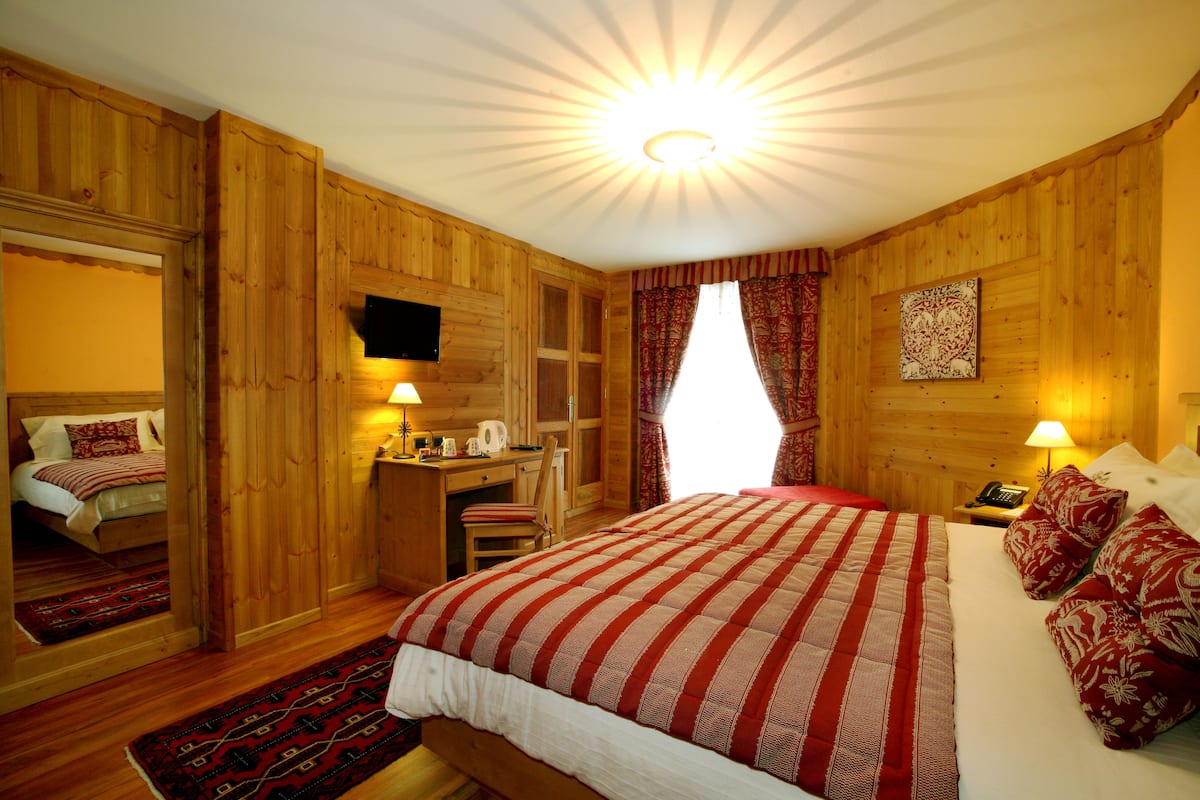 A wooden-paneled room with a large bed, a desk, and a television.