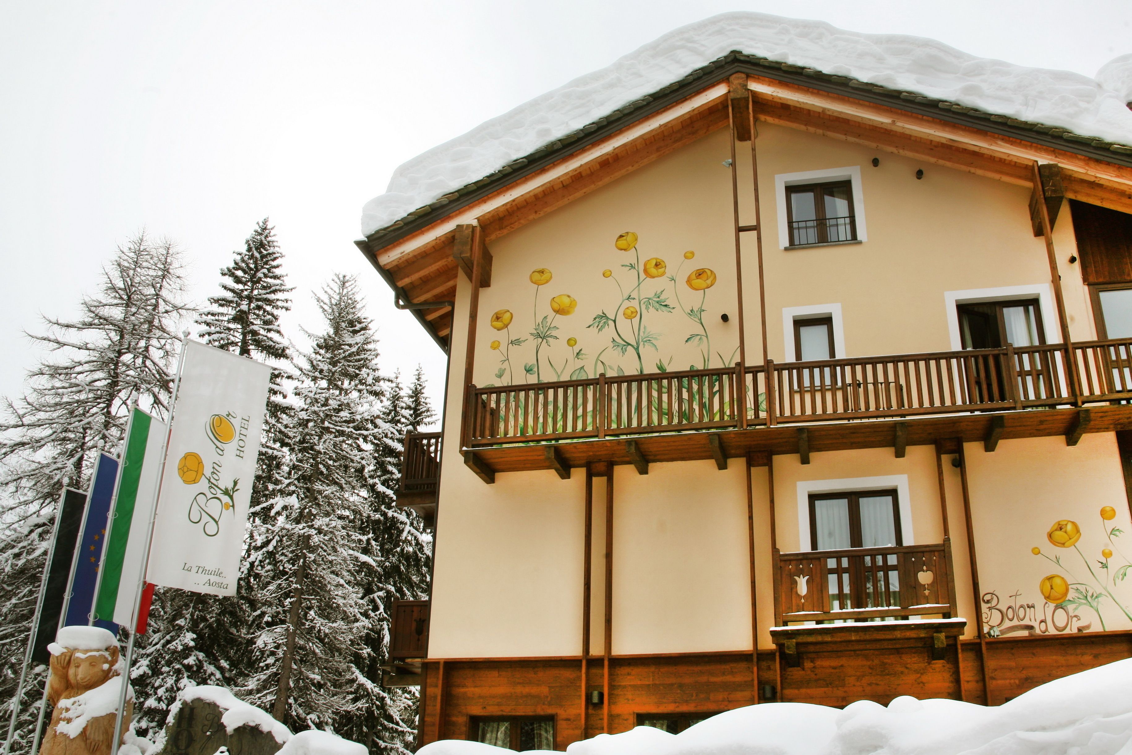 A hotel with a balcony and a snow-covered roof.