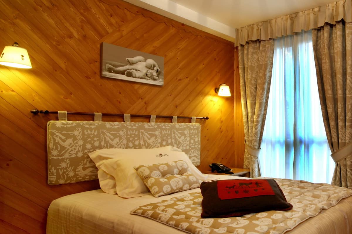 A neatly made bed with patterned bedding and pillows, a bedside table with a lamp, and a framed picture on the wall.