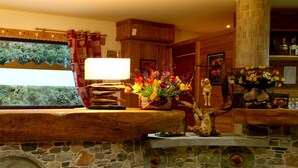 Une cheminée en pierre avec un manteau en bois, une lampe et un vase de fleurs.