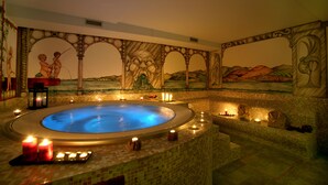 Un bain à remous aux motifs de mosaïque, entouré de bougies et d’éléments décoratifs.