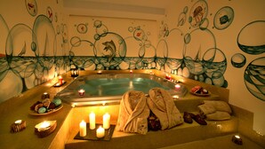 Un espace spa comprenant un bain à remous, des bougies, des serviettes et des œuvres d’art décoratives murales.