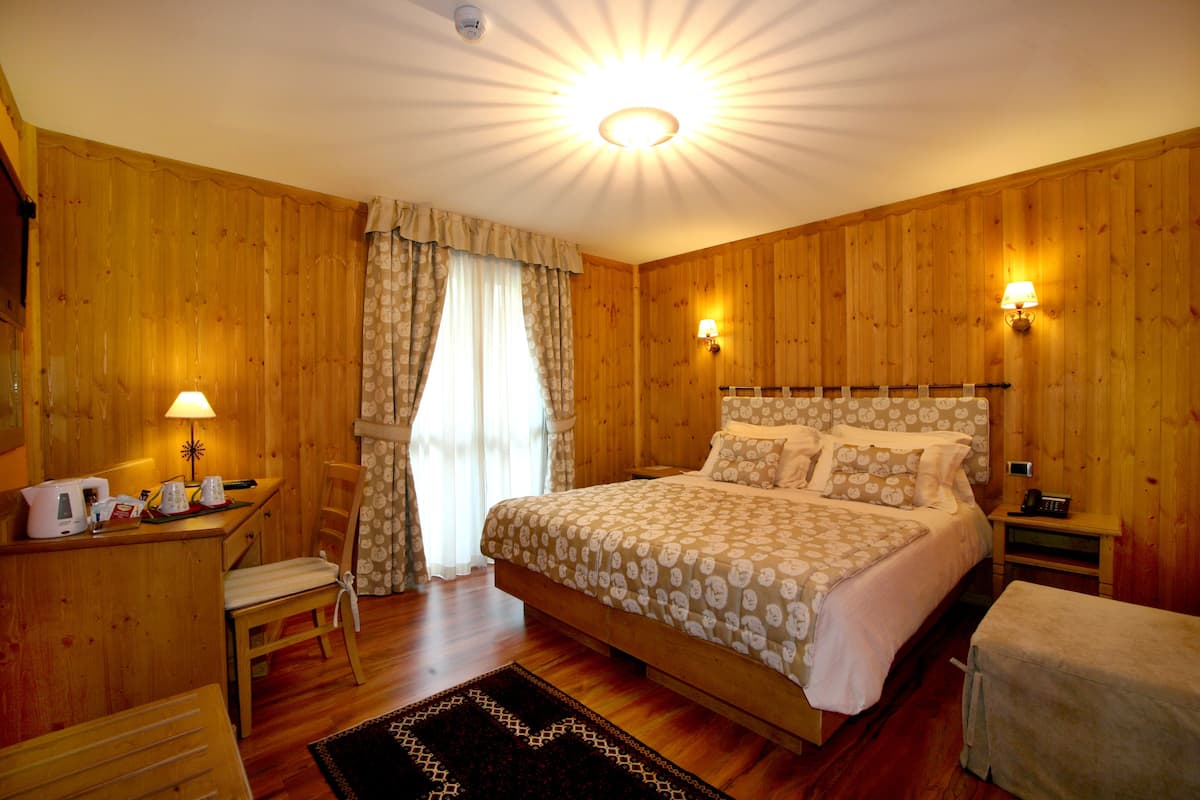 A wooden-paneled room with a bed, a desk, and a chair.