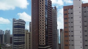 A high-rise building with a checkered facade, surrounded by other tall buildings. - Flat Residencial La Perla (Fortaleza)