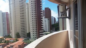 A high-rise building with multiple floors, a balcony with a curved railing, and a window with a light fixture. - Flat Residencial La Perla (Fortaleza)