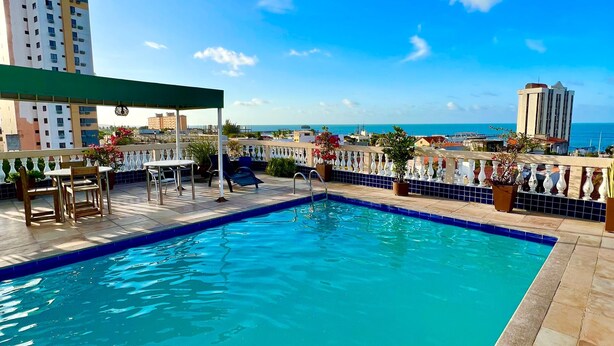 A rooftop pool with a view of the ocean and cityscape. - Algarve Praia Hotel (Fortaleza)