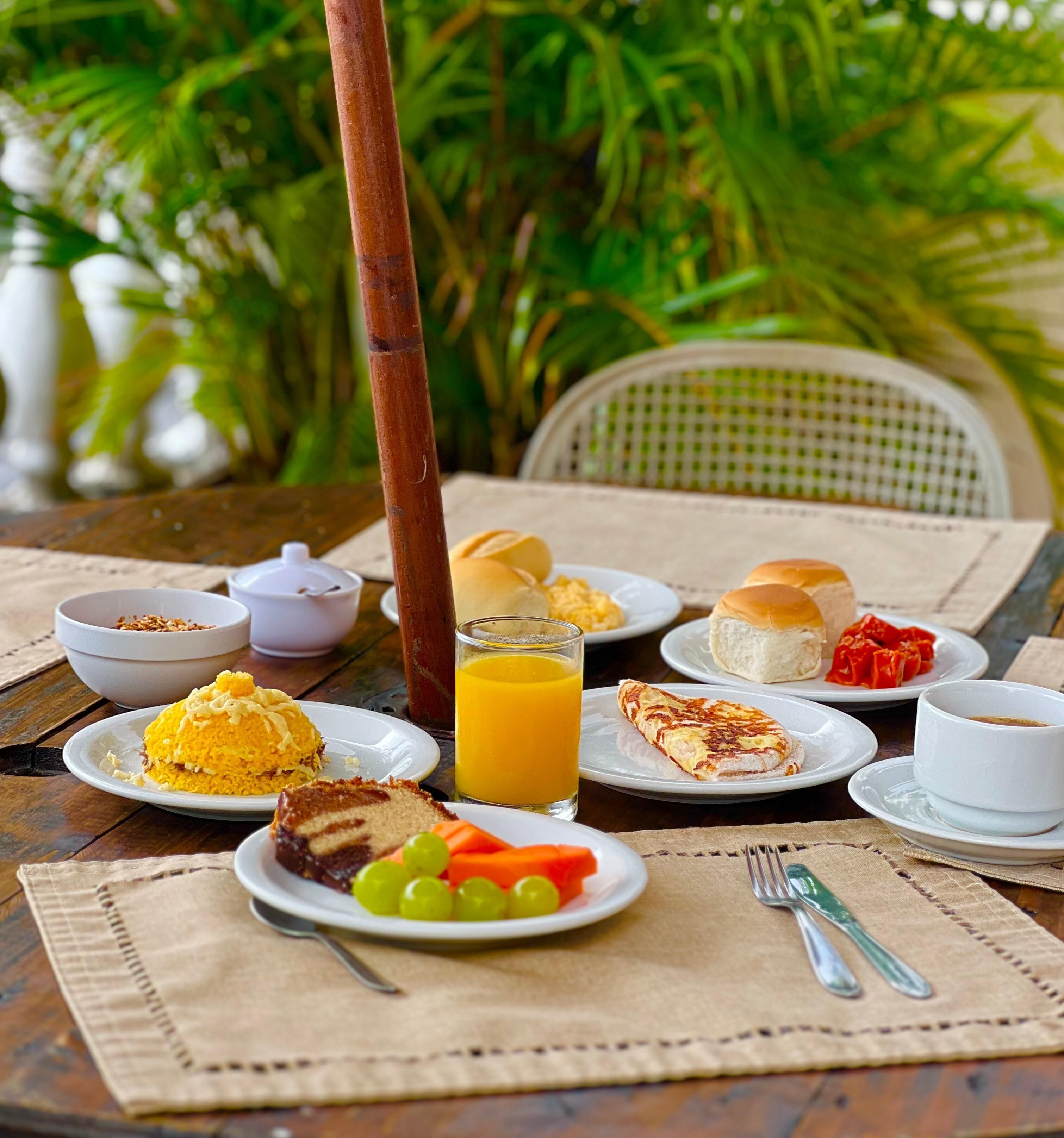 A table set with various dishes including a plate of yellow rice, a slice of cake, and a glass of orange juice.