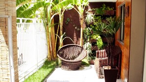 A clean, modern entrance with a tiled floor, a white fence, and lush greenery including banana trees and potted plants. - Algarve Praia Hotel (Fortaleza)