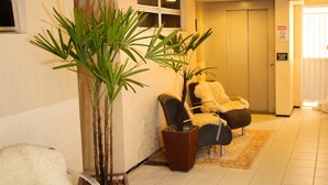 A hotel lobby with a reception desk, a potted plant, a sofa, and a door with a sign. - Algarve Praia Hotel (Fortaleza)