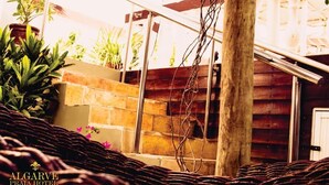 A wicker bed with a brick wall and wooden staircase in the background. - Algarve Praia Hotel (Fortaleza)