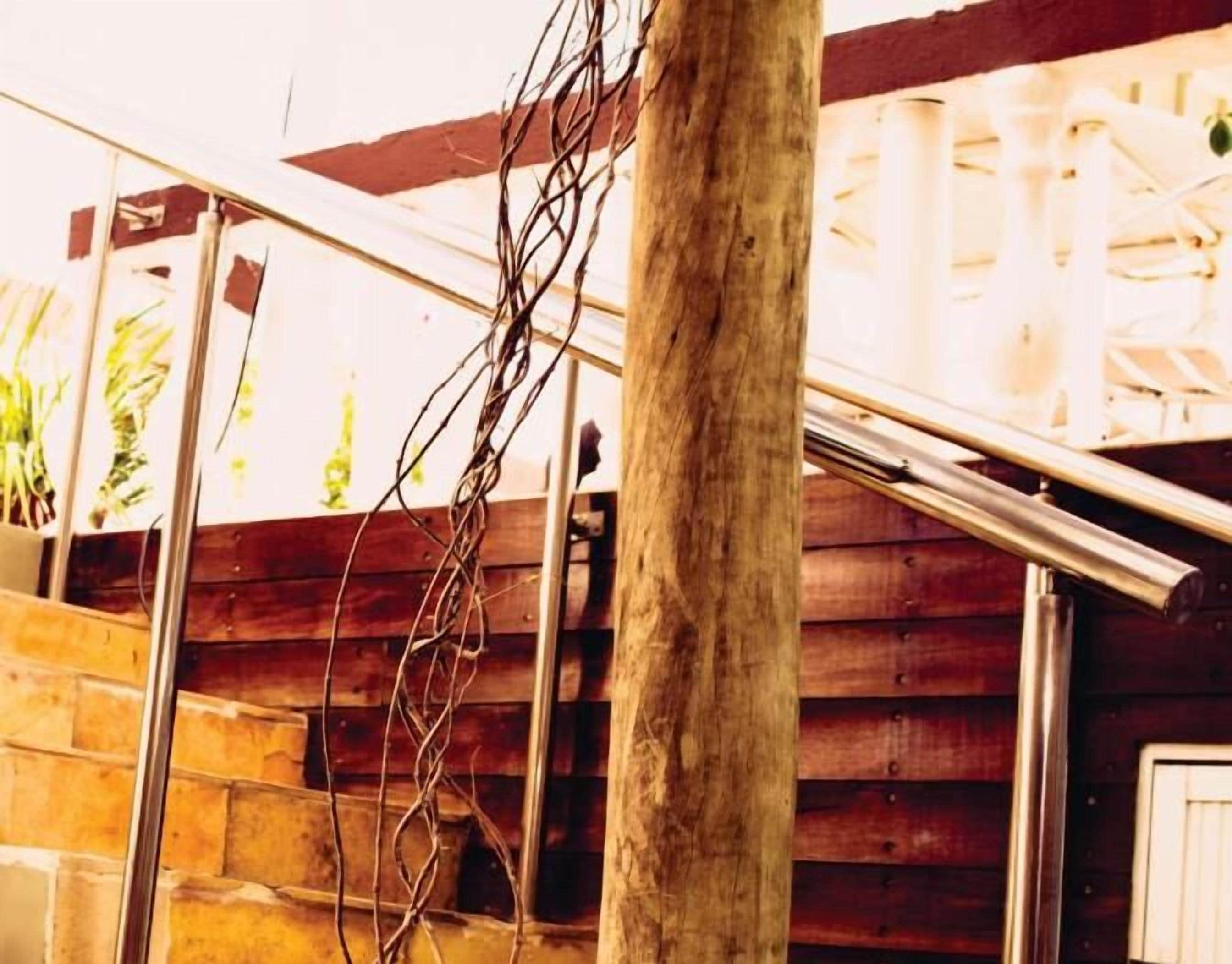 Un escalier en bois avec des rampes en métal et un mur en pierre.