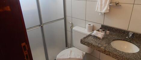 Kylpyhuone, jossa on wc, pesuallas ja seinälle ripustettu pyyhe.