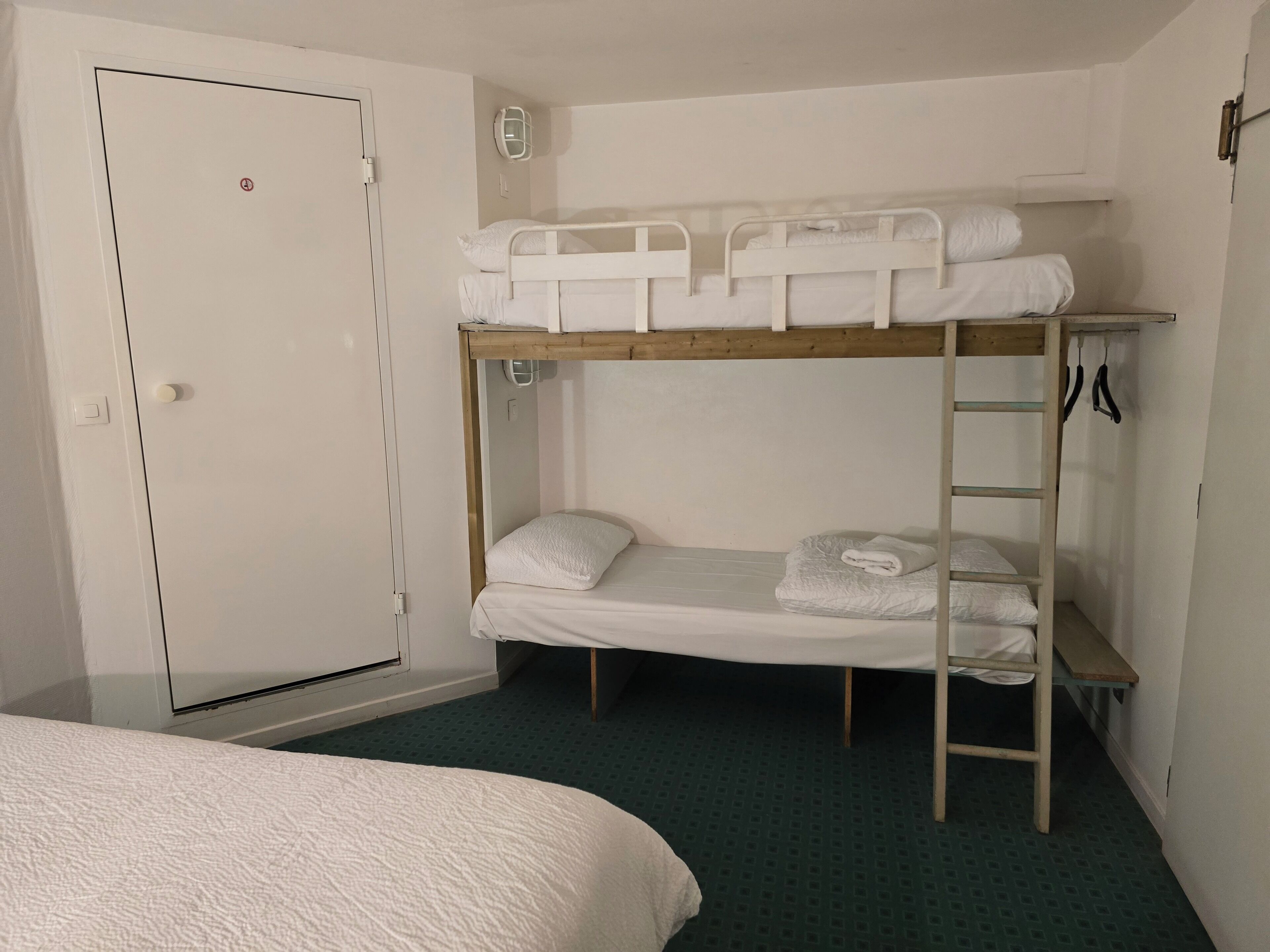 A bunk bed room with a door, a small table, and a pair of scissors on the wall.