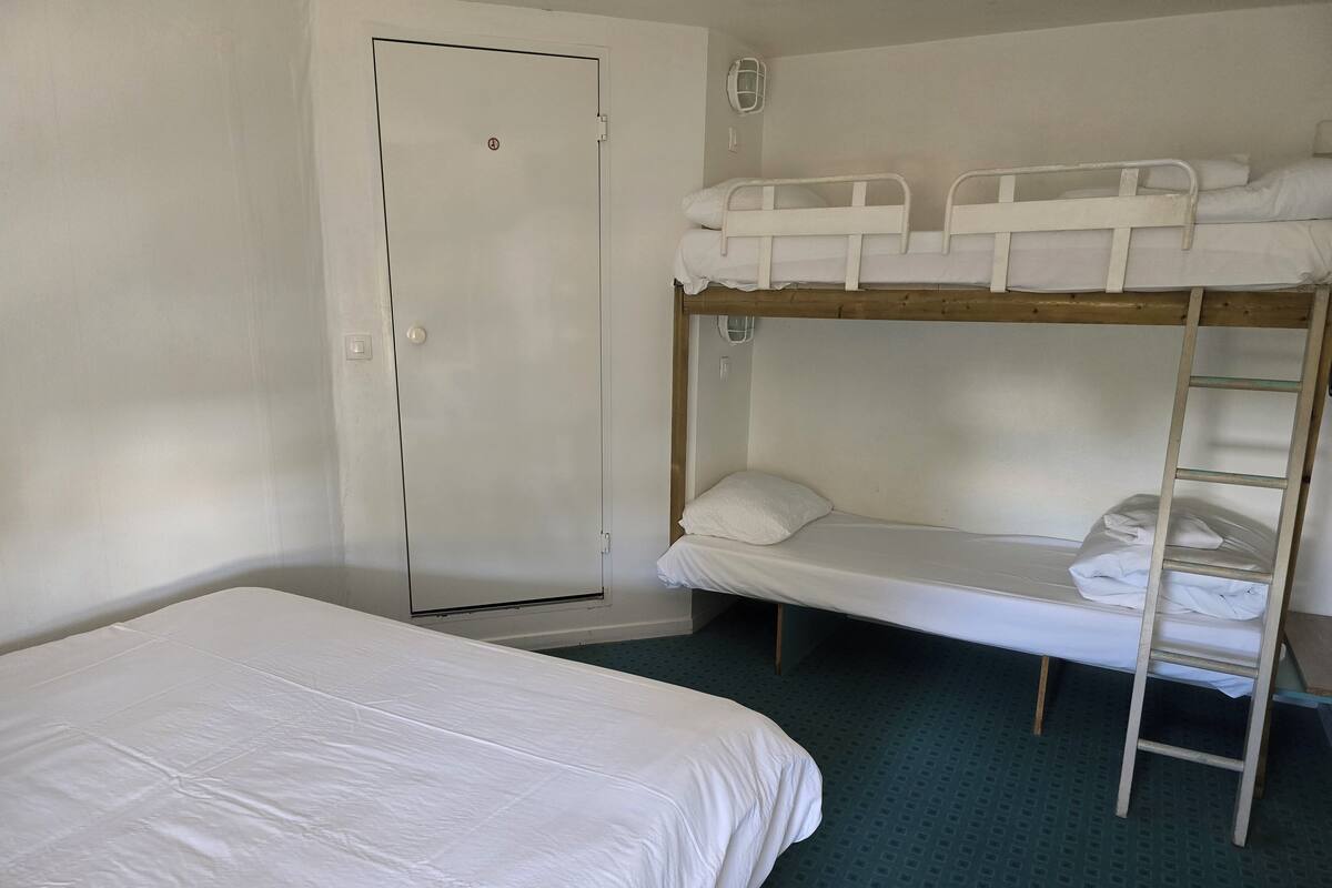 A room with a bunk bed, a single bed, and a door.