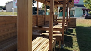 A covered outdoor seating area with wooden benches and a metal roof structure. - Brit Hotel Essentiel Poitiers – Gare du Futuroscope (Jaunay-Marigny)