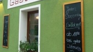 A building with a green facade, a sign reading "Gasthof", and a chalkboard with a menu listing prices. - Hotel-Gasthof-Fellner (Furth im Wald)